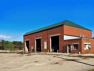 Brick building with open garage bays at the former transfer station.