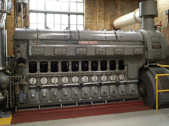 Close-up of a large gray diesel engine with a row of gauges along its side.