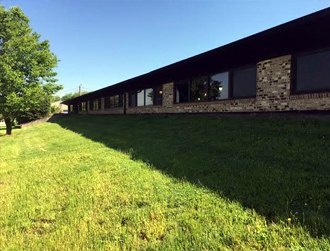 Long single-story brick building beside a mowed lawn.