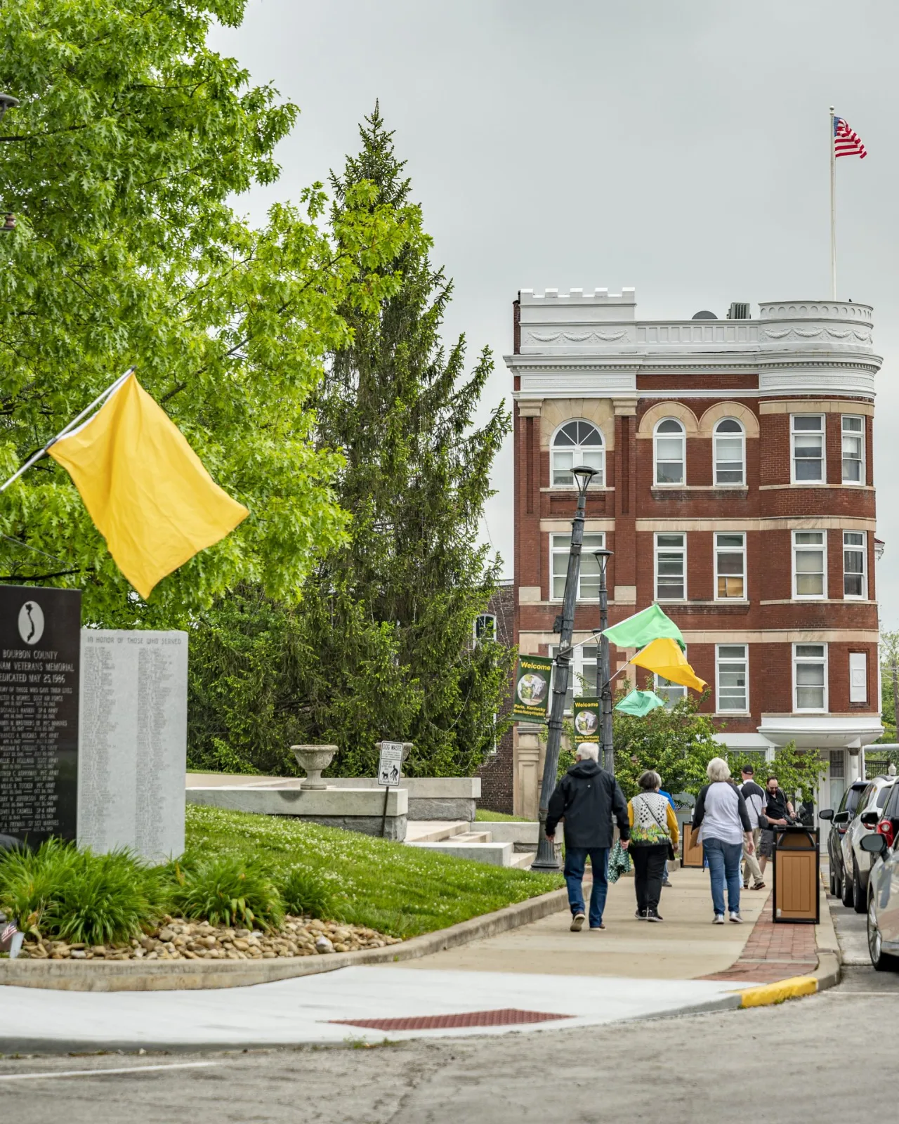 Historic brick building and a memorial along a downtown Paris sidewalk