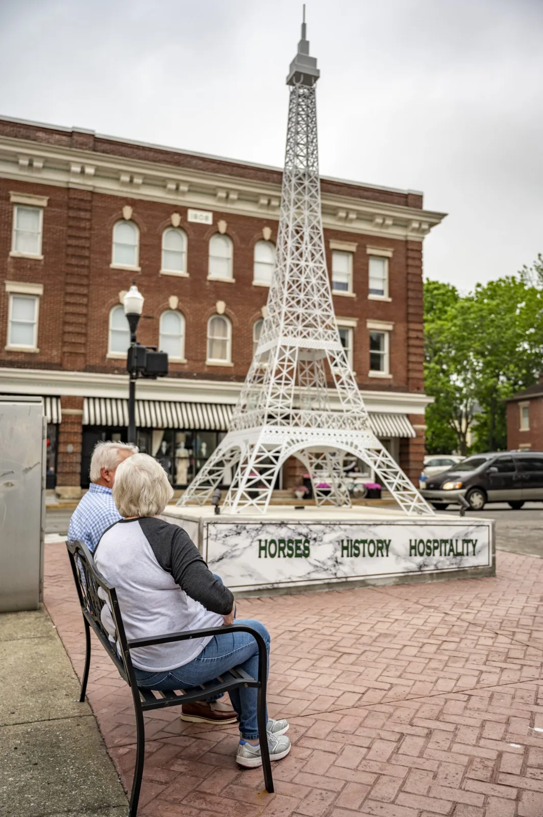Eiffel Tower replica in a downtown Paris courtyard, with two people seated on a bench