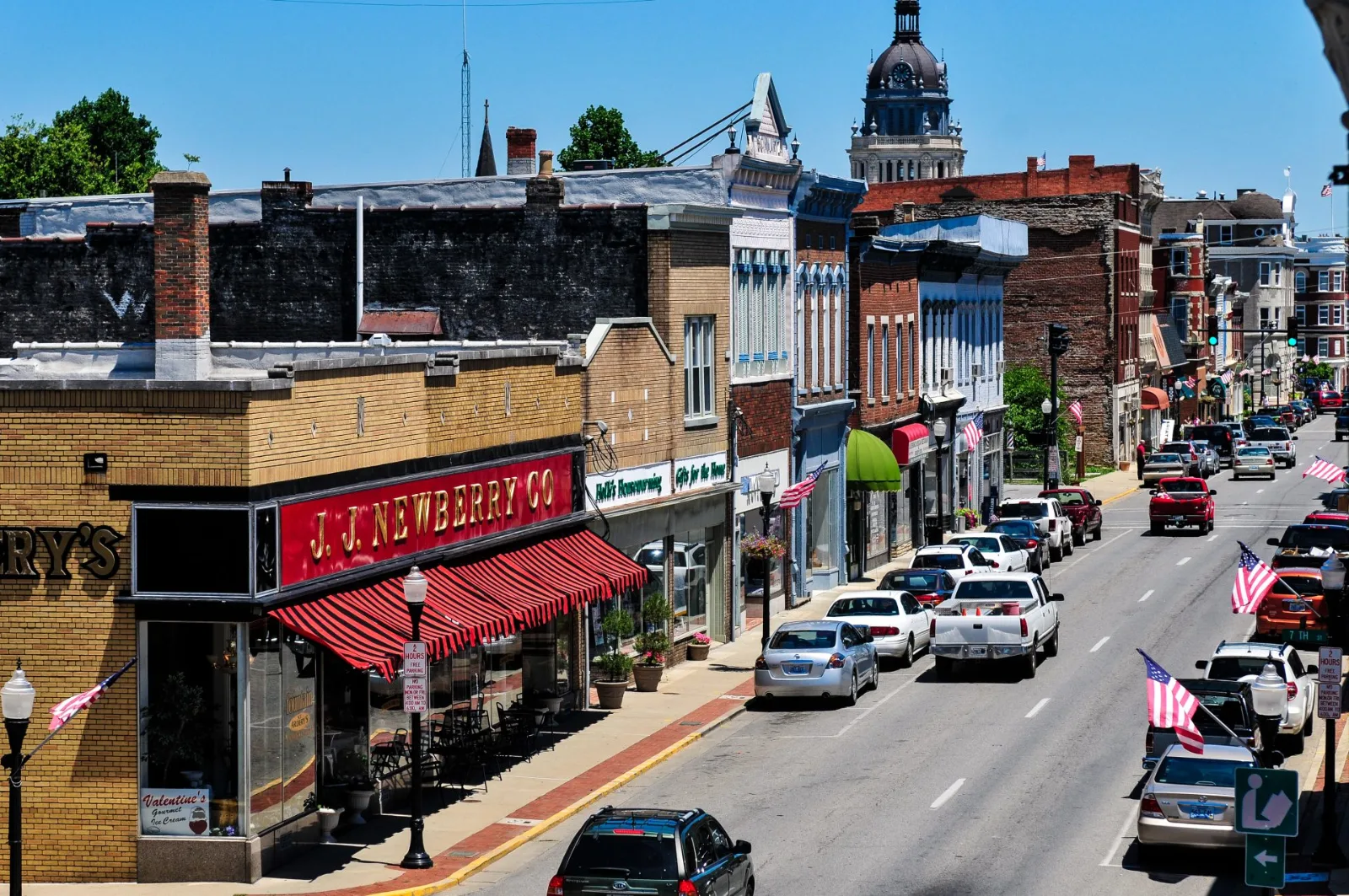 Main Street in downtown Paris lined with storefronts, with the Bourbon County Courthouse dome in the distance