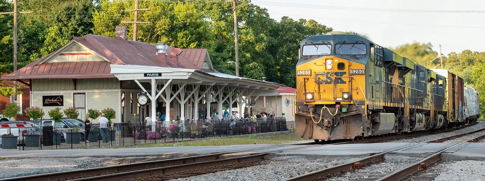 A train passes the historic Paris train depot as diners sit on the porch