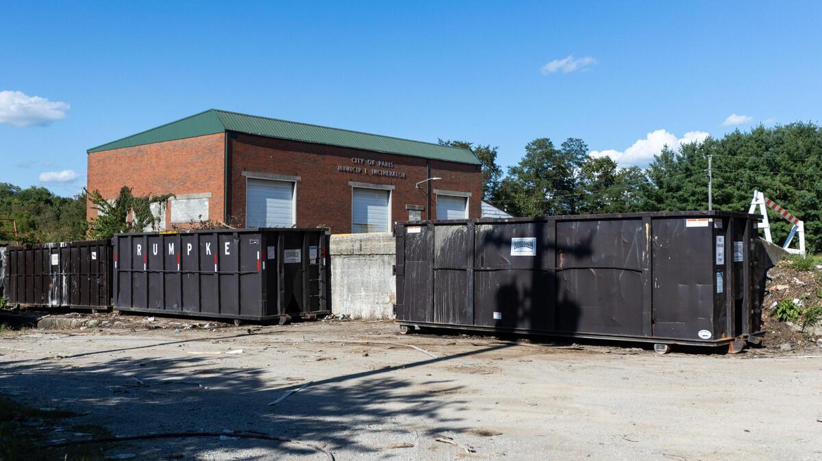 The former Paris transfer station: a brick building with a row of large dumpsters in front.